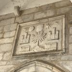 Placa, feita em mármore branco, localizada em cima da entrada do Paços Medievais de Concelho, no interior do Castelo de Estremoz, hoje Galeria de Arte.